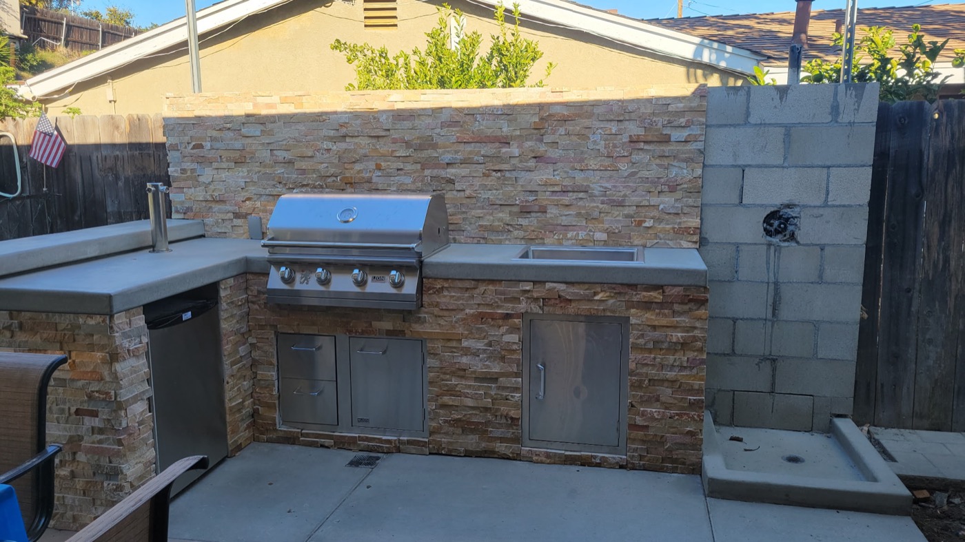 Custom outdoor BBQ island with stone veneer and stainless appliances