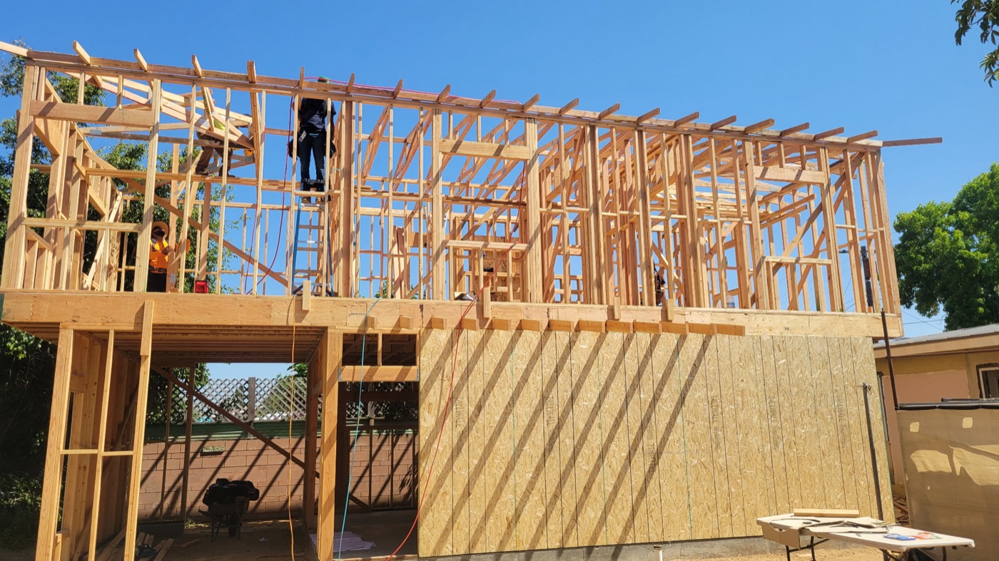 New home construction — crew framing roof structure under blue sky