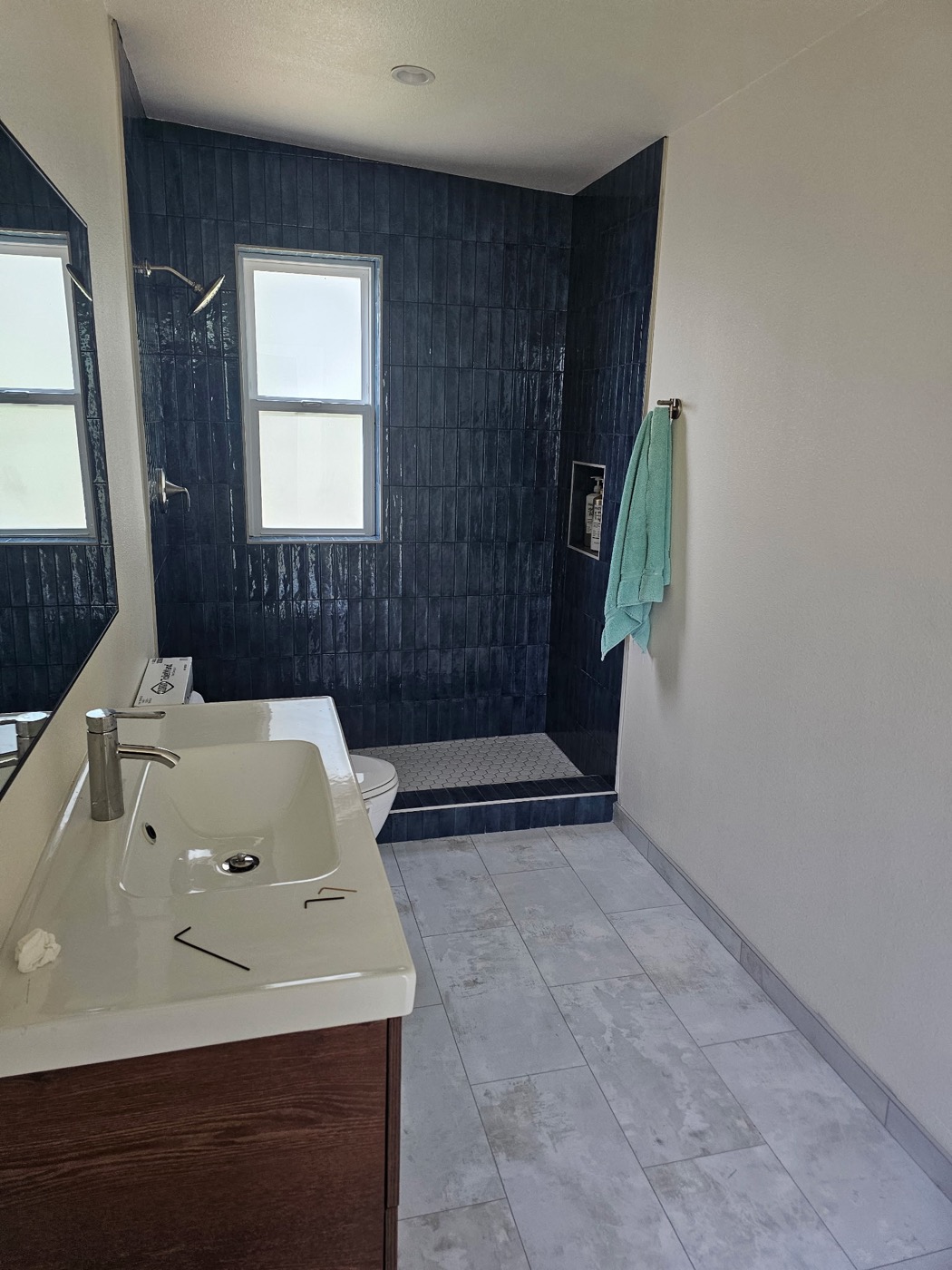 Completed bathroom remodel with navy tile walk-in shower and modern vanity