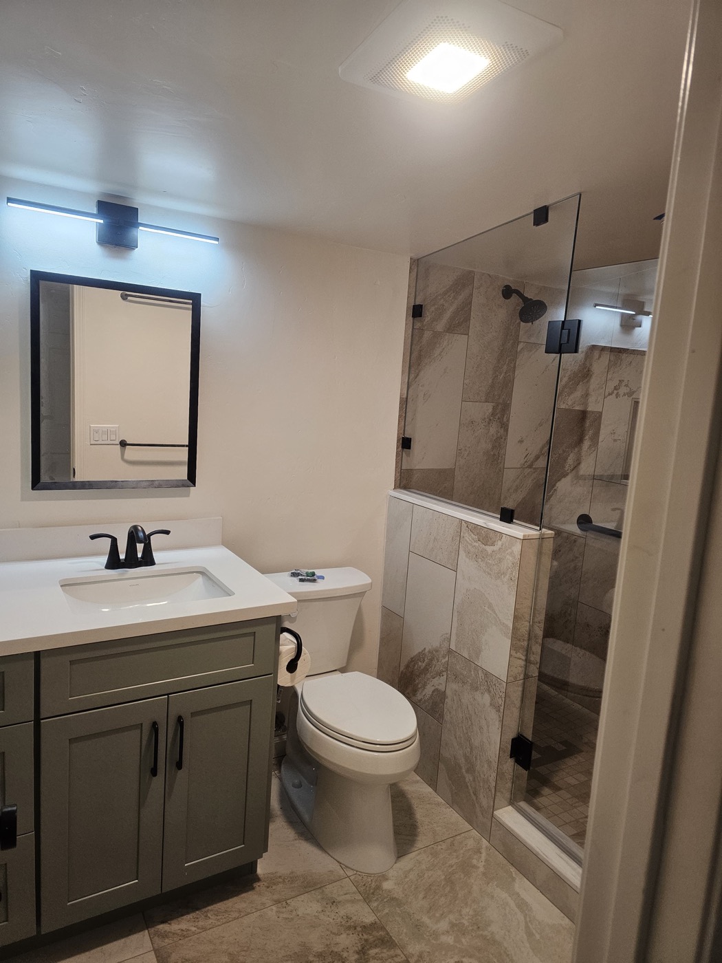 Completed bathroom with sage vanity and marble tile shower