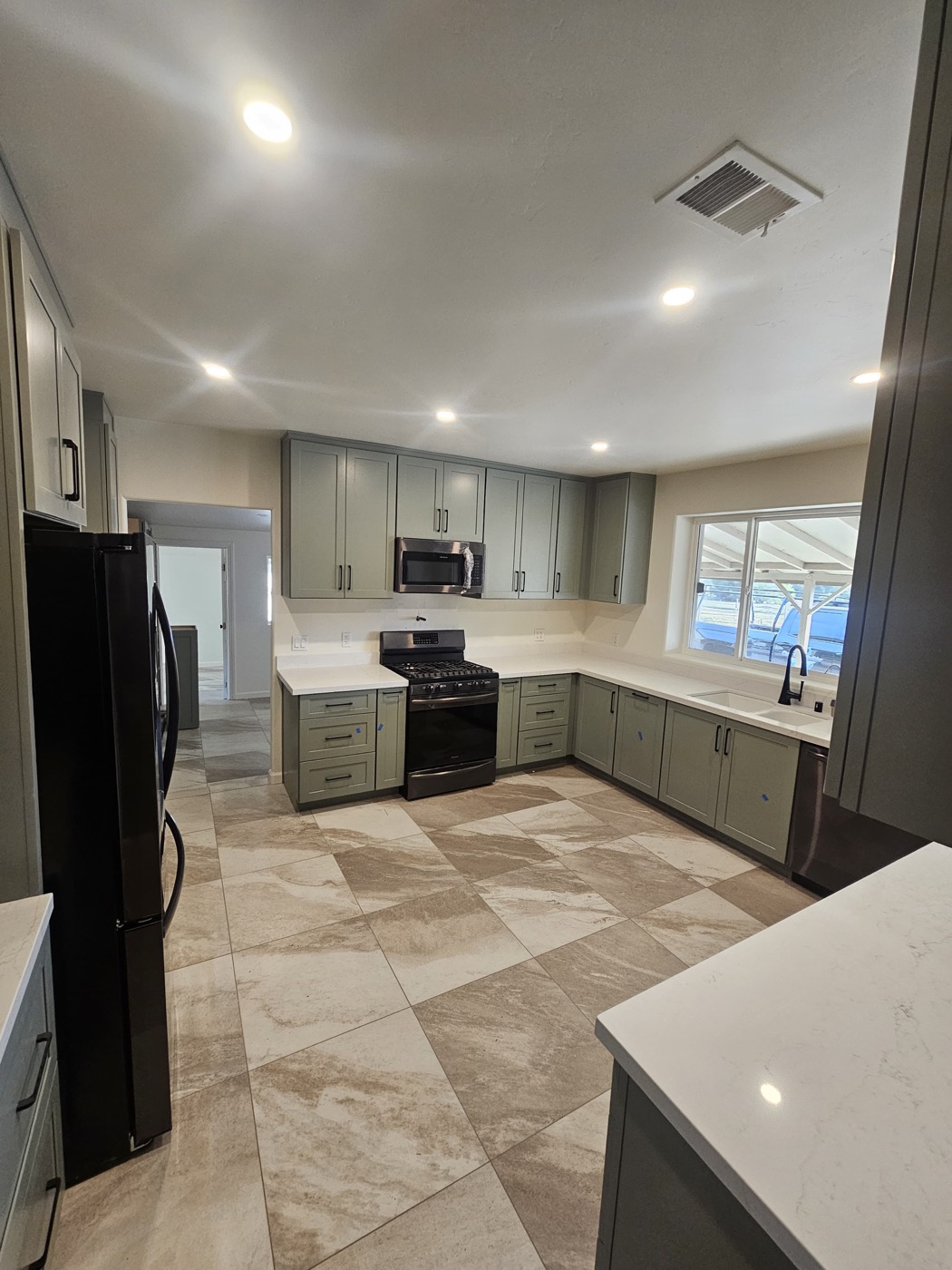 Completed kitchen with sage green cabinets and quartz countertops