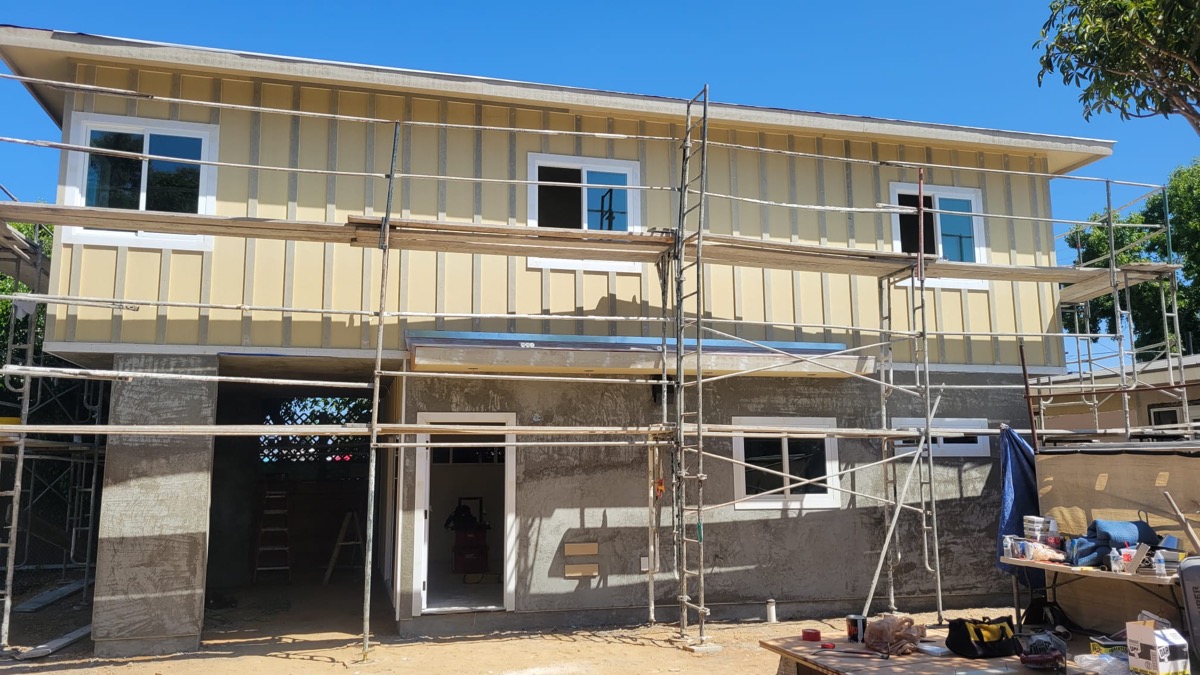 Two-story home addition at stucco phase with scaffolding