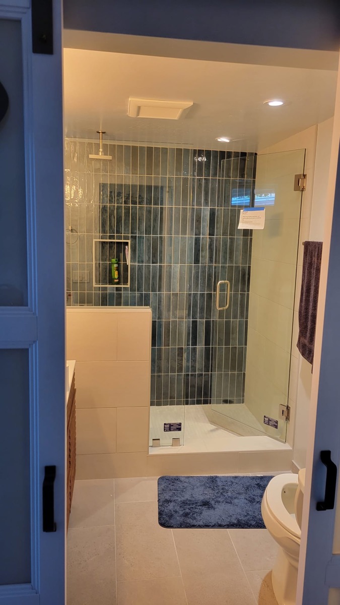 Bathroom remodel with green subway tile shower and frameless glass door
