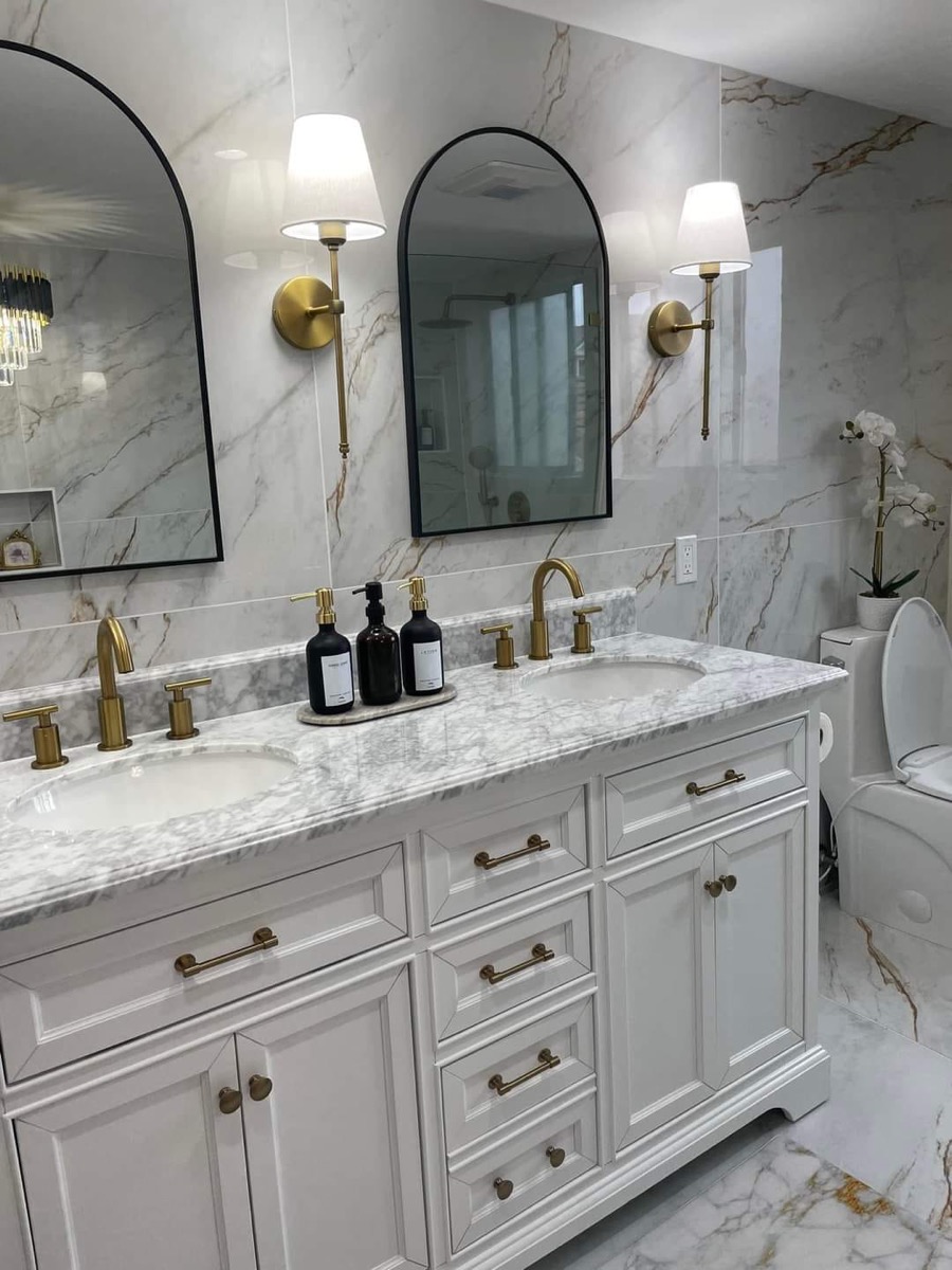 Luxury master bathroom with marble vanity, gold faucets and marble tile walls