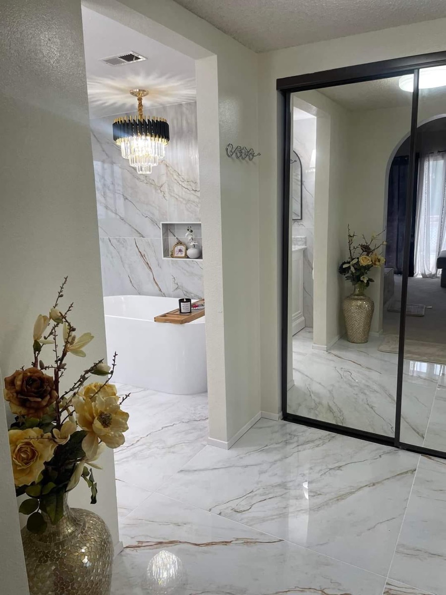 Master suite with marble floors, chandelier and freestanding tub through archway