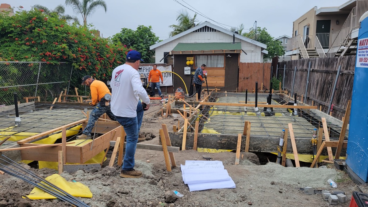 Crew pouring concrete foundation with rebar form work