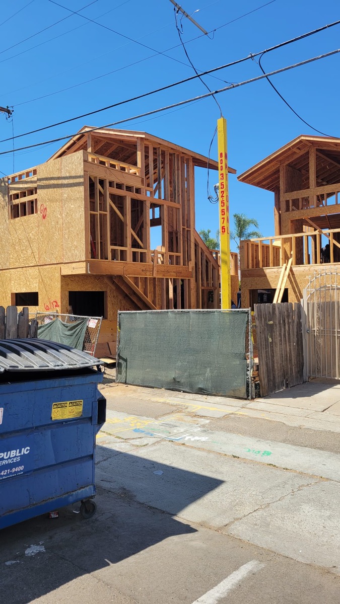 New build construction from street showing framing and dumpster