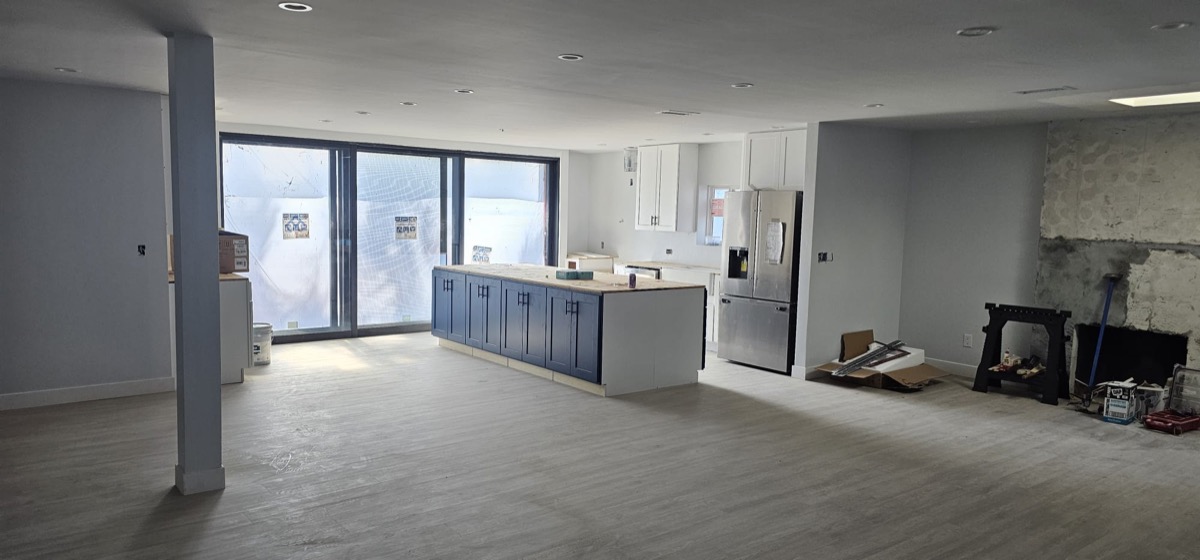 New build open-concept kitchen with blue island cabinets and large windows