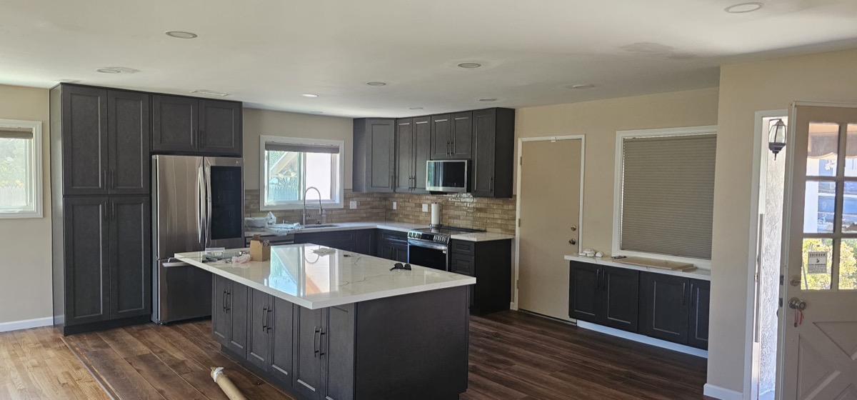 Completed kitchen with dark cabinets, quartz island and stainless appliances
