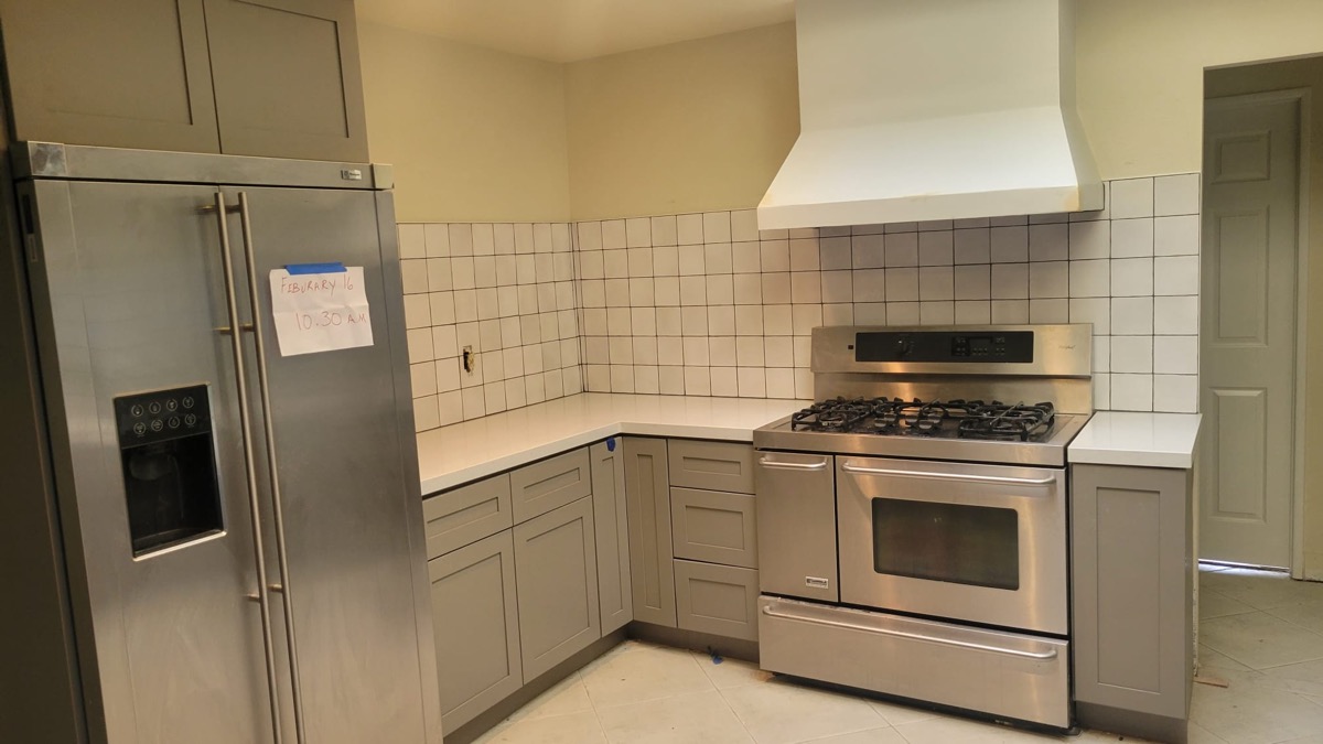 Kitchen remodel with custom range hood, gray cabinets and stainless appliances